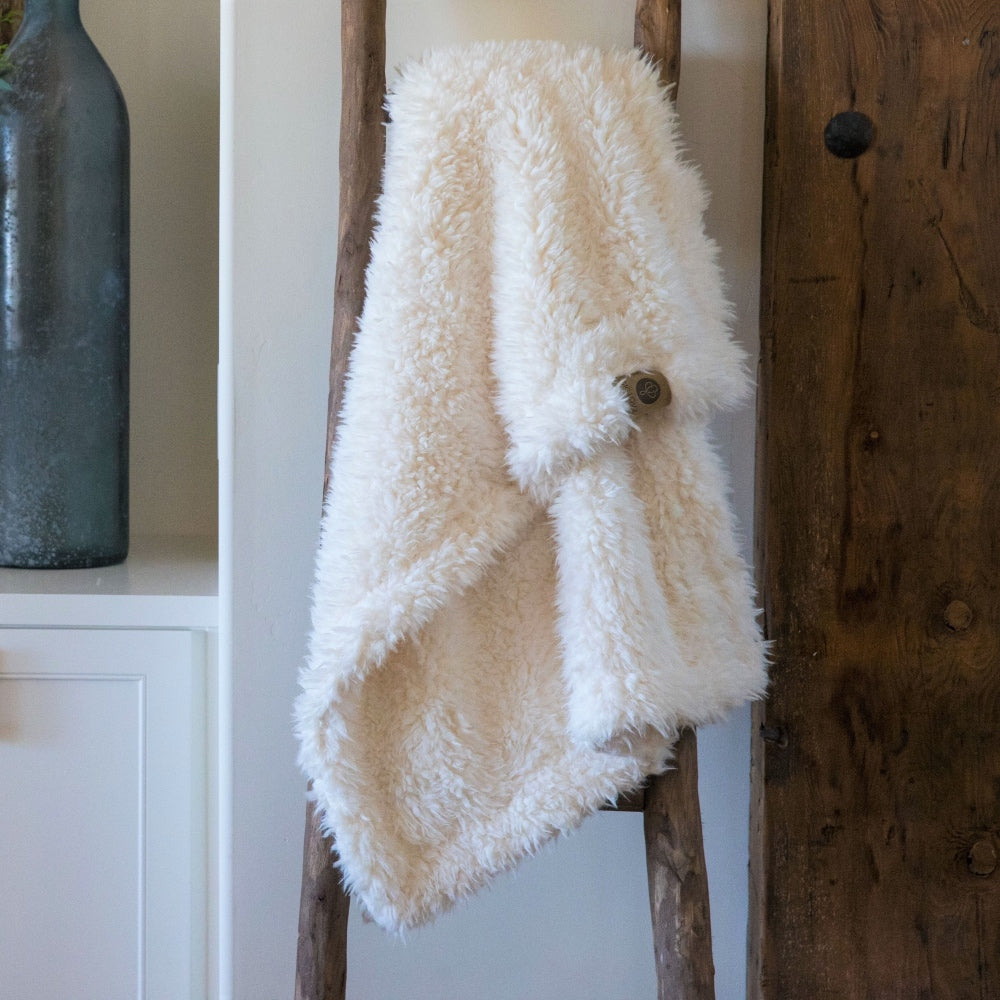 Little Guardian Angel blanket in Whisper White, llama fabric, on wooden ladder in front of white cabinets BIG LOViE