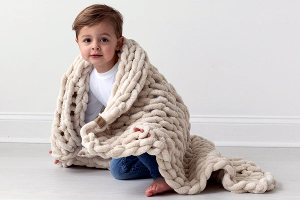 Little child wrapped up in BIG LOViE Infinite Chunky Knit Minky Little Sand blanket.