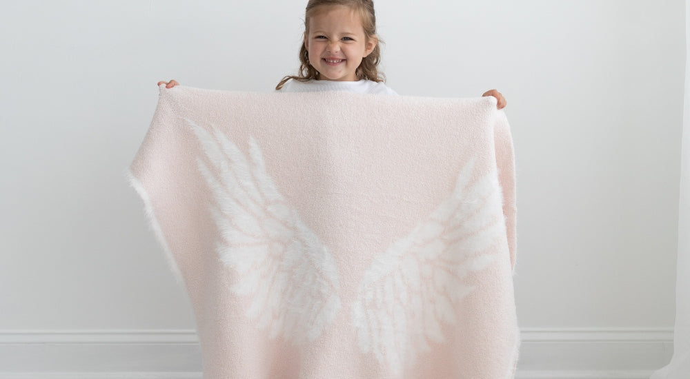 Small smiling child holding BIG LOViE Little Wings in pink.