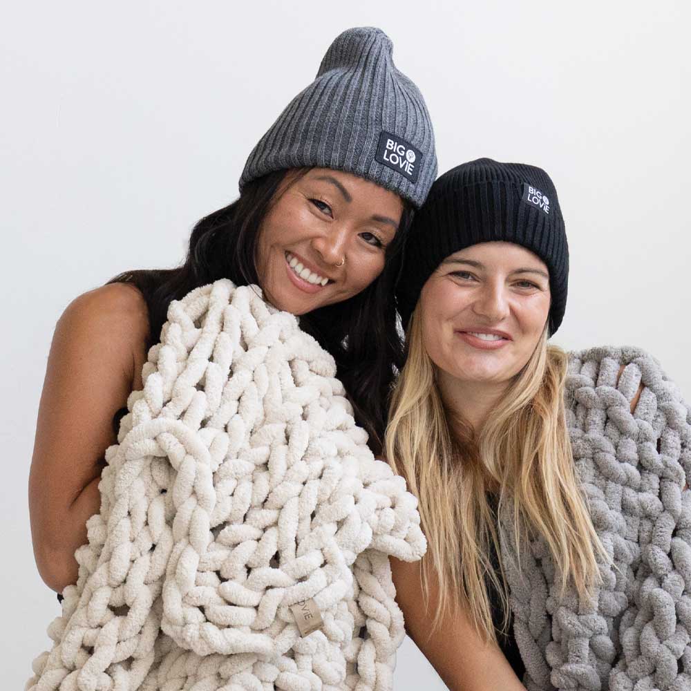 BIG LOViE Fun and Badass Beanies on smiling women, wrapped up in Infinite Chunky Knit Minky Blankets