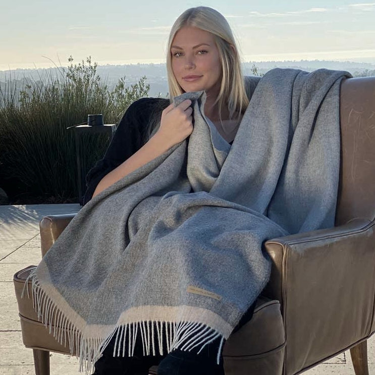 Woman covered with BIG LOViE Soul Coco 100 percent baby alpaca blanket sitting outside.