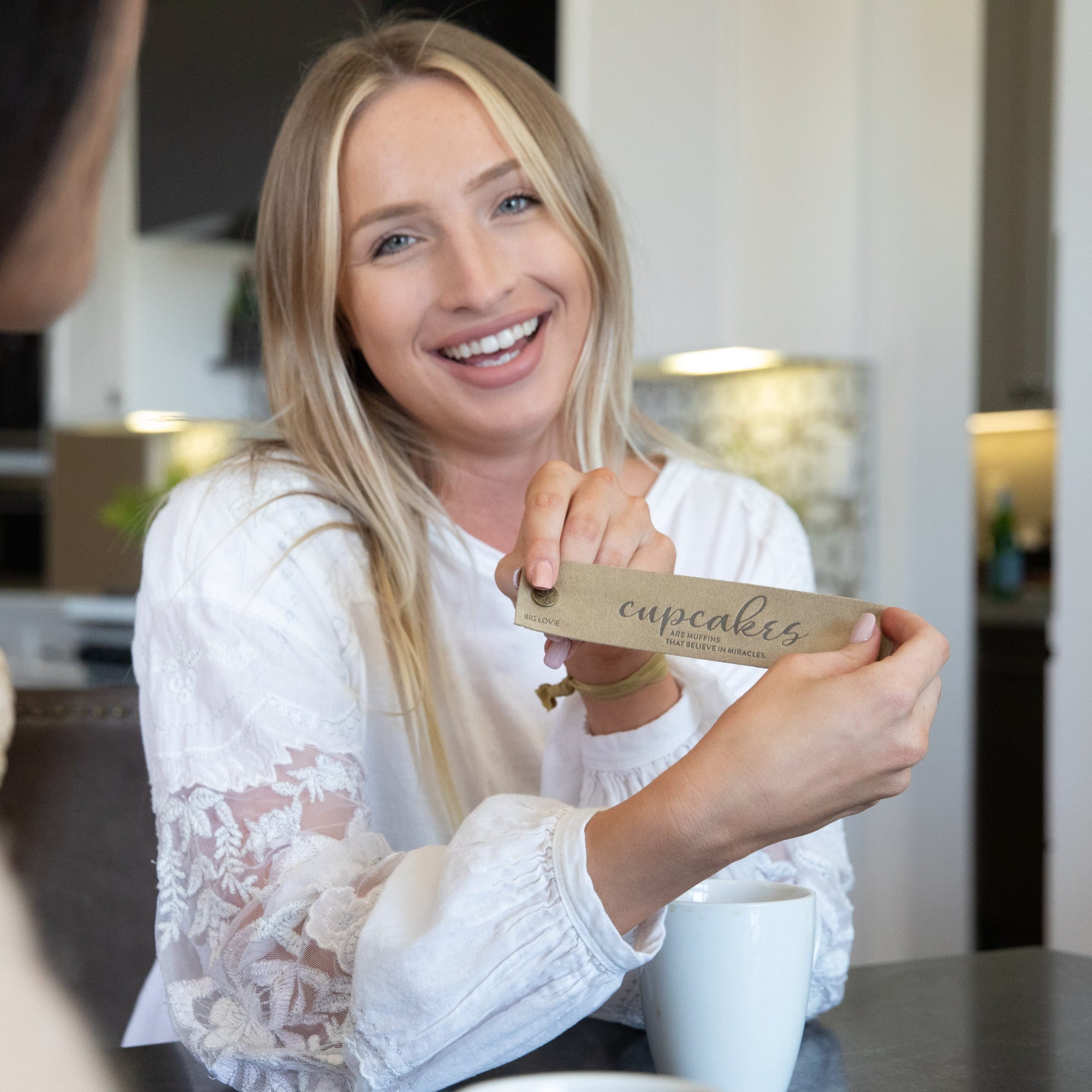 Woman in white smiling, holding up LoveSnap