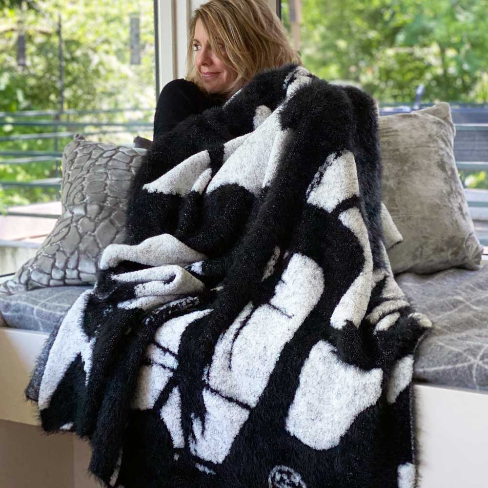 Smiling woman wrapped in BIG LOViE Jumper Maybach Dream Collection blanket in White Winds.