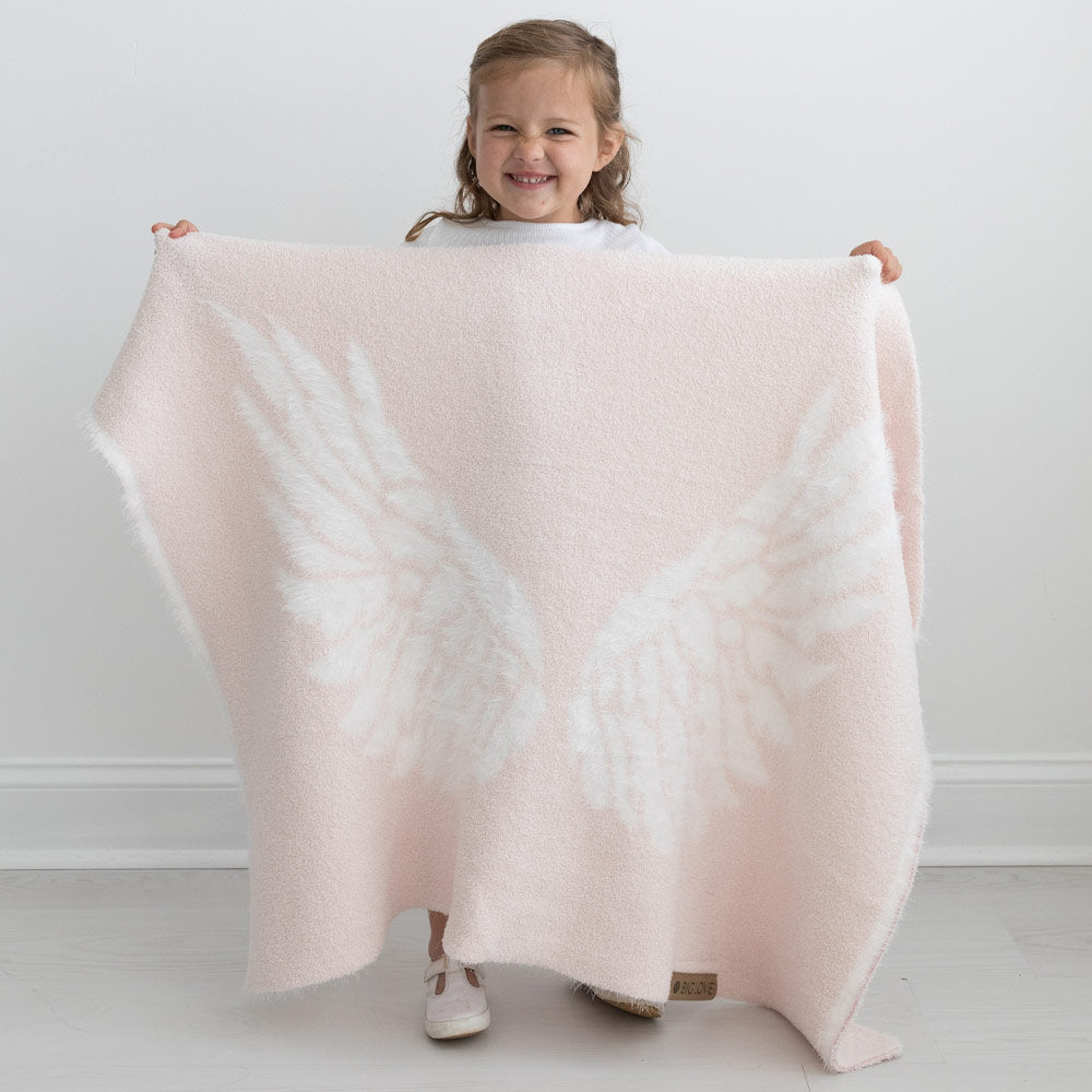 Small smiling child holding BIG LOViE Little Wings in pink.