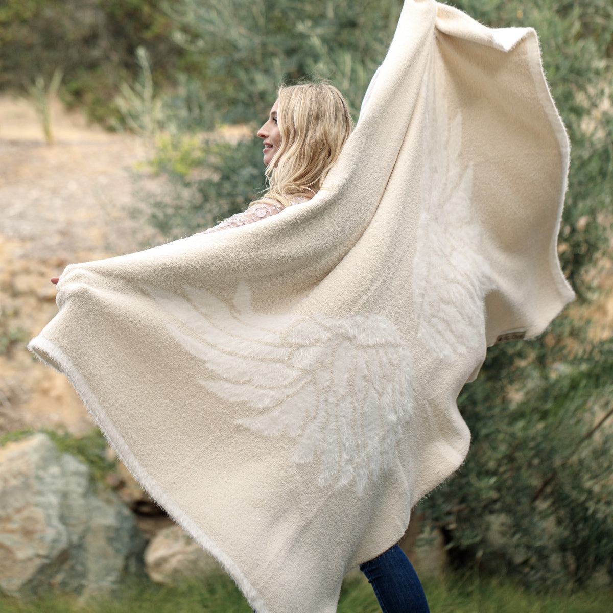 Woman spreading her wings in the BIG LOViE Wings Blanket from the Dream Collection, micro-chenille and feather yarn.