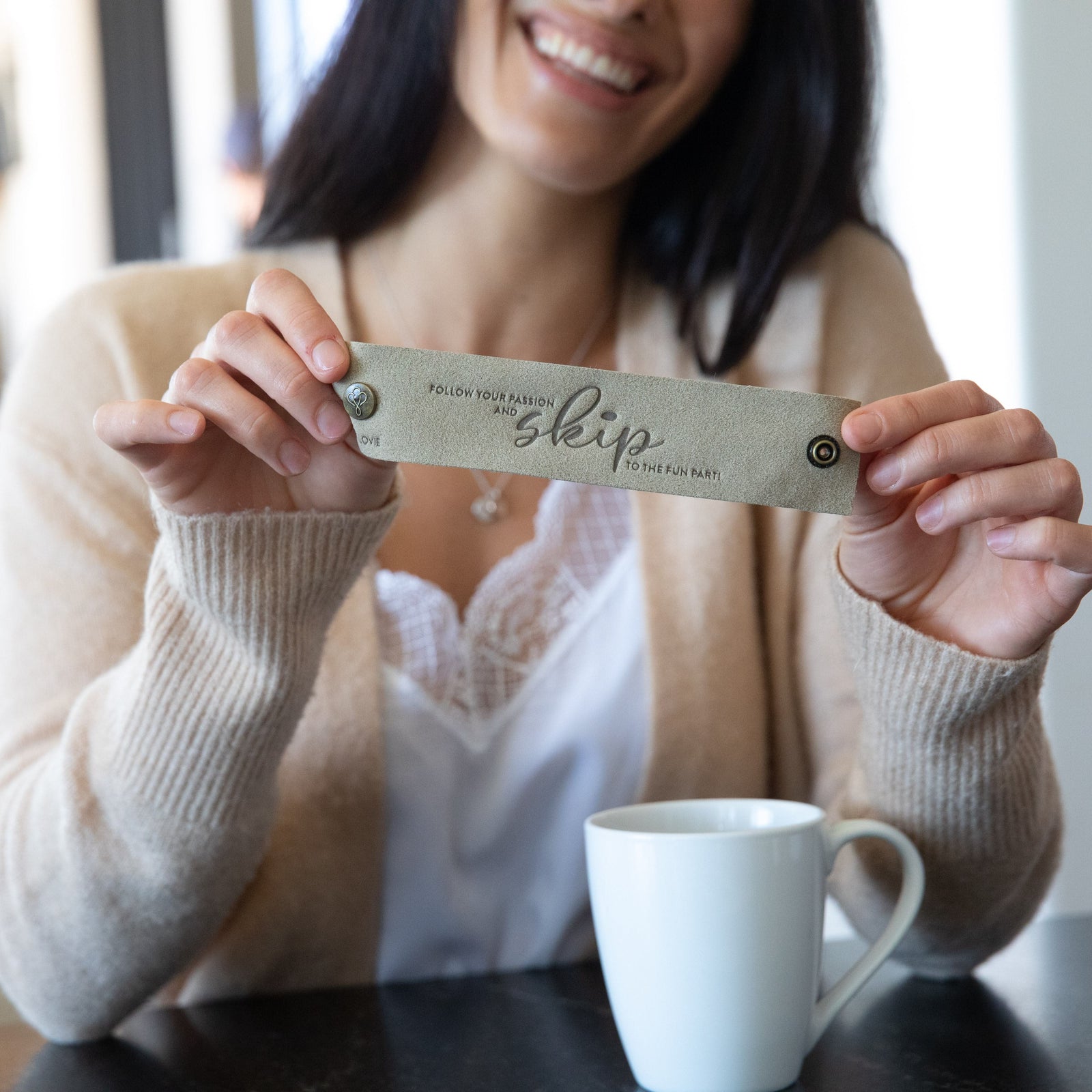 Woman smiling with cup of coffee, holding up LoveSnap