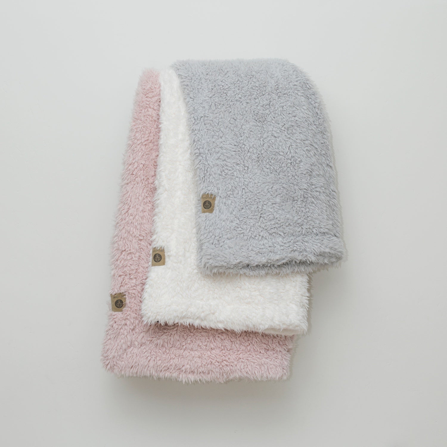 Stacked llama fabric blankets from the Guardian Angel Collection in: Silver Cloud, Whisper White, Dusty Pink