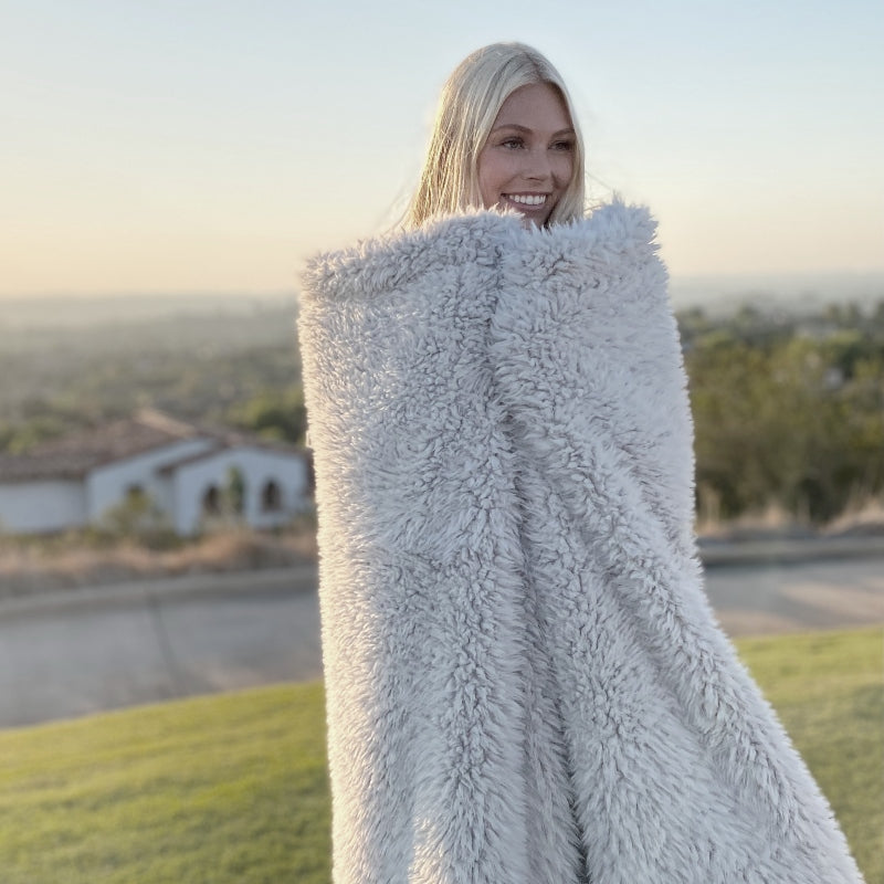 Woman wrapped in BIG LOViE Angel Plush Blanket in silver cloud.