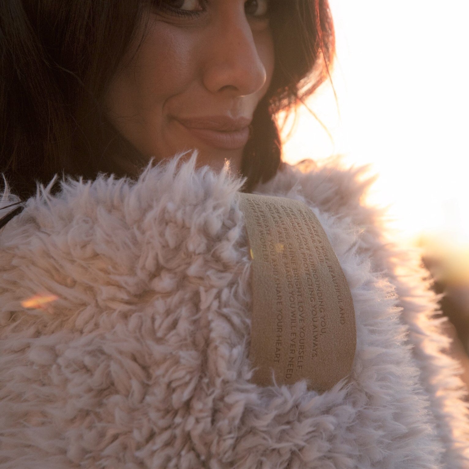 Woman smiling with big guardian angel blanket in dusty pink over her shoulder, close up of lovesnap 