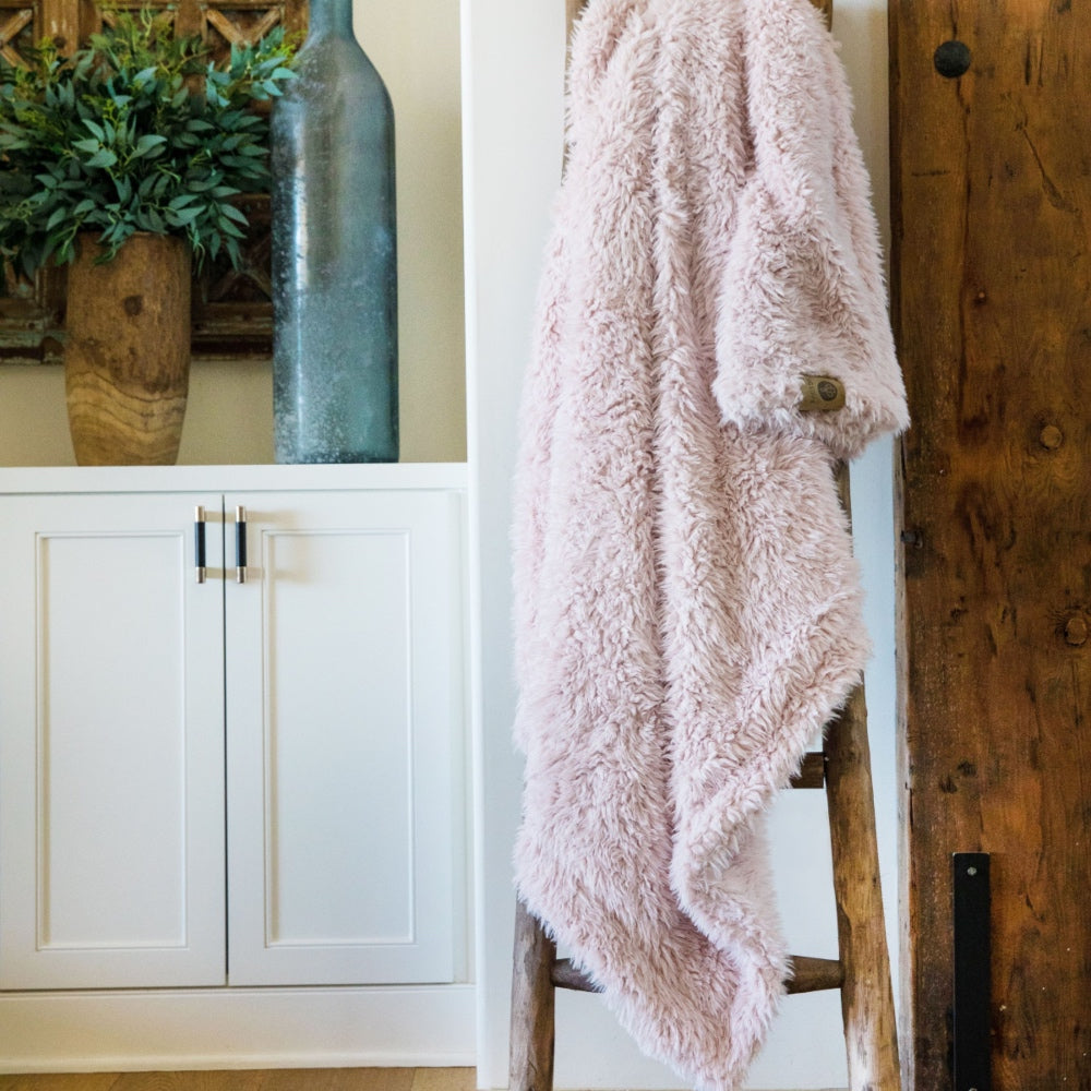 Big Guardian Angel blanket in Dusty Pink, llama fabric, on a wooden ladder in front of white cabinets