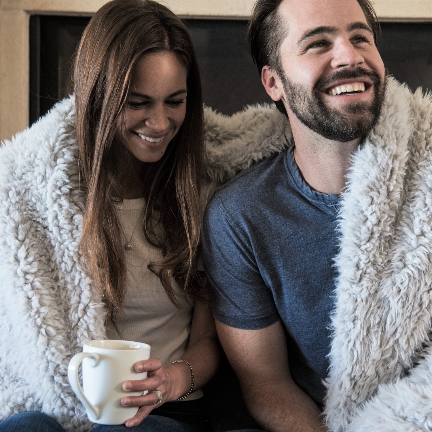 A couple cuddling in their Big Guardian Angel Blanket in Silver Cloud, plush llama fabric