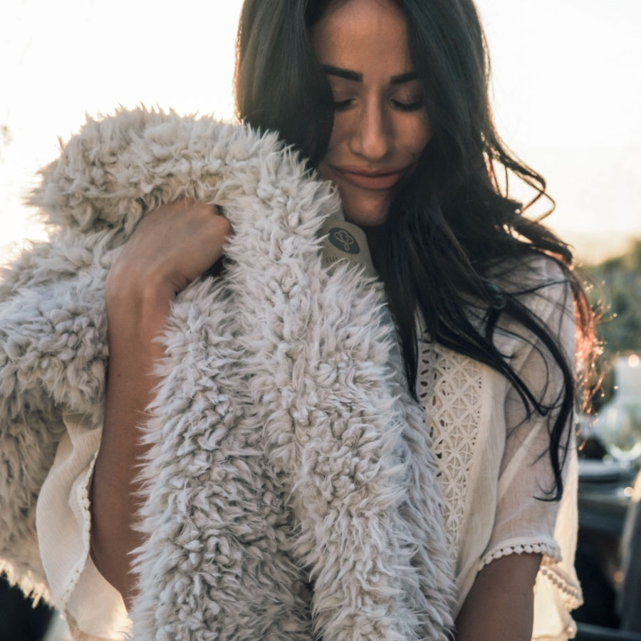 A woman hugging her plush llama fabric blanket, from The Big Guardian Angel Collection in Silver Cloud