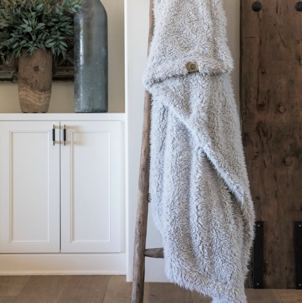 Big Guardian Angel blanket in Silver Cloud, llama fabric, on a wooden ladder in front of white cabinets