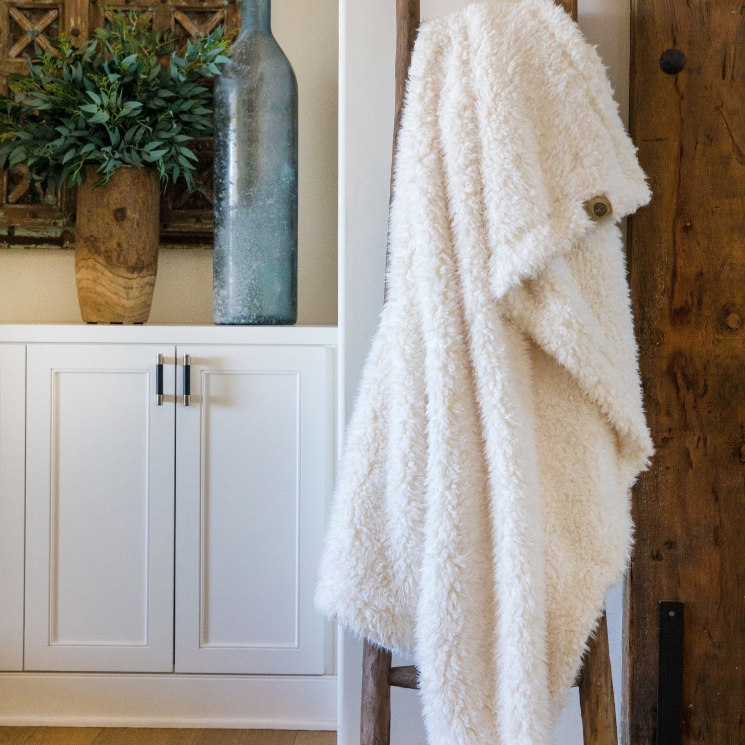 BIG LOViE Big Guardian Angel blanket in Whisper White, llama fabric, on a wooden ladder in front of white cabinets