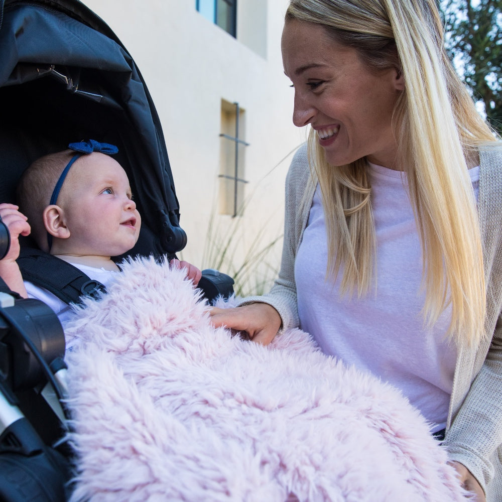 Mother looking at her baby girl in a stroller, wrapped in Little Guardian Angel Blanket in Dusty Pink, nursery blanket