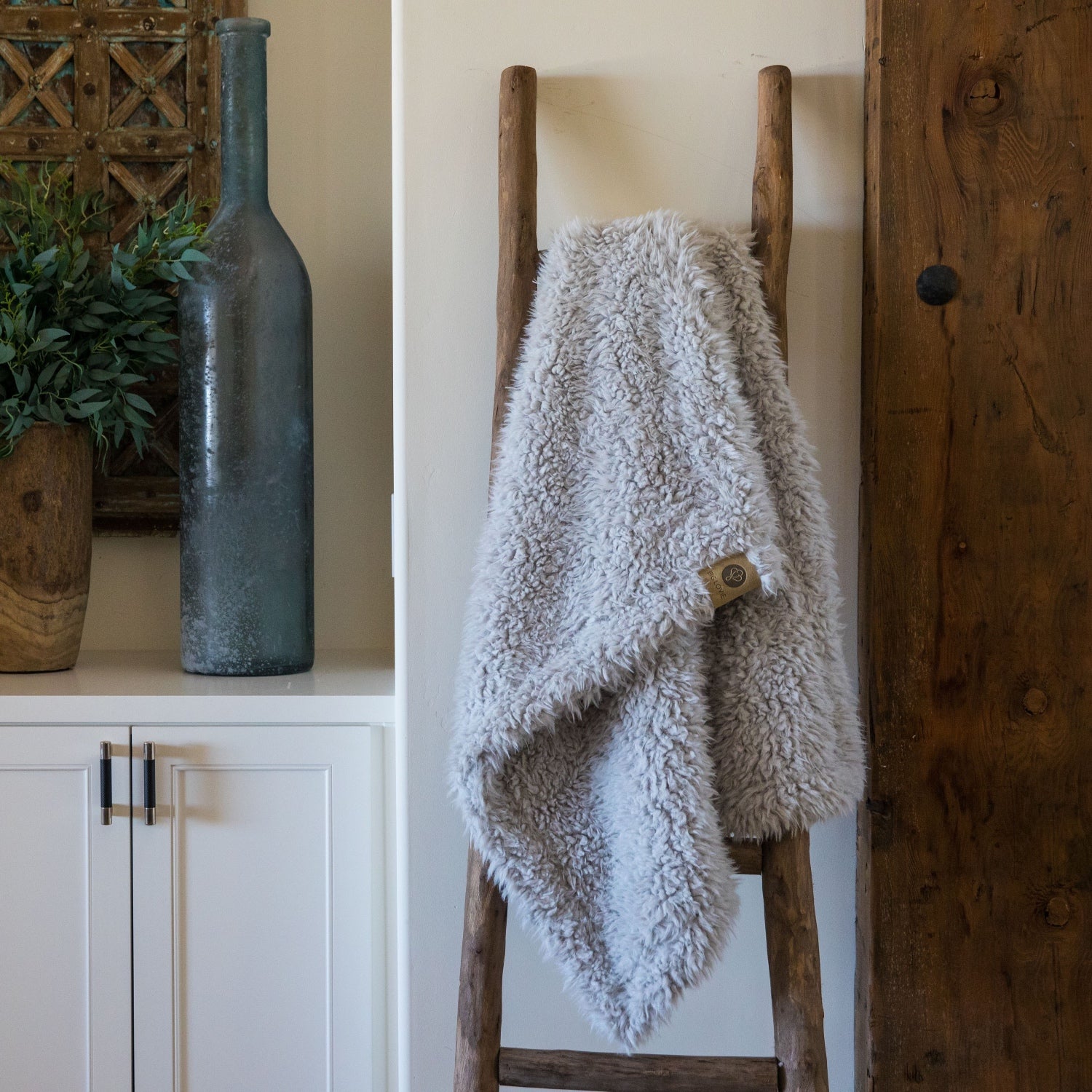  Little Guardian Angel blanket in Silver Cloud, llama fabric, on wooden ladder in front of white cabinets