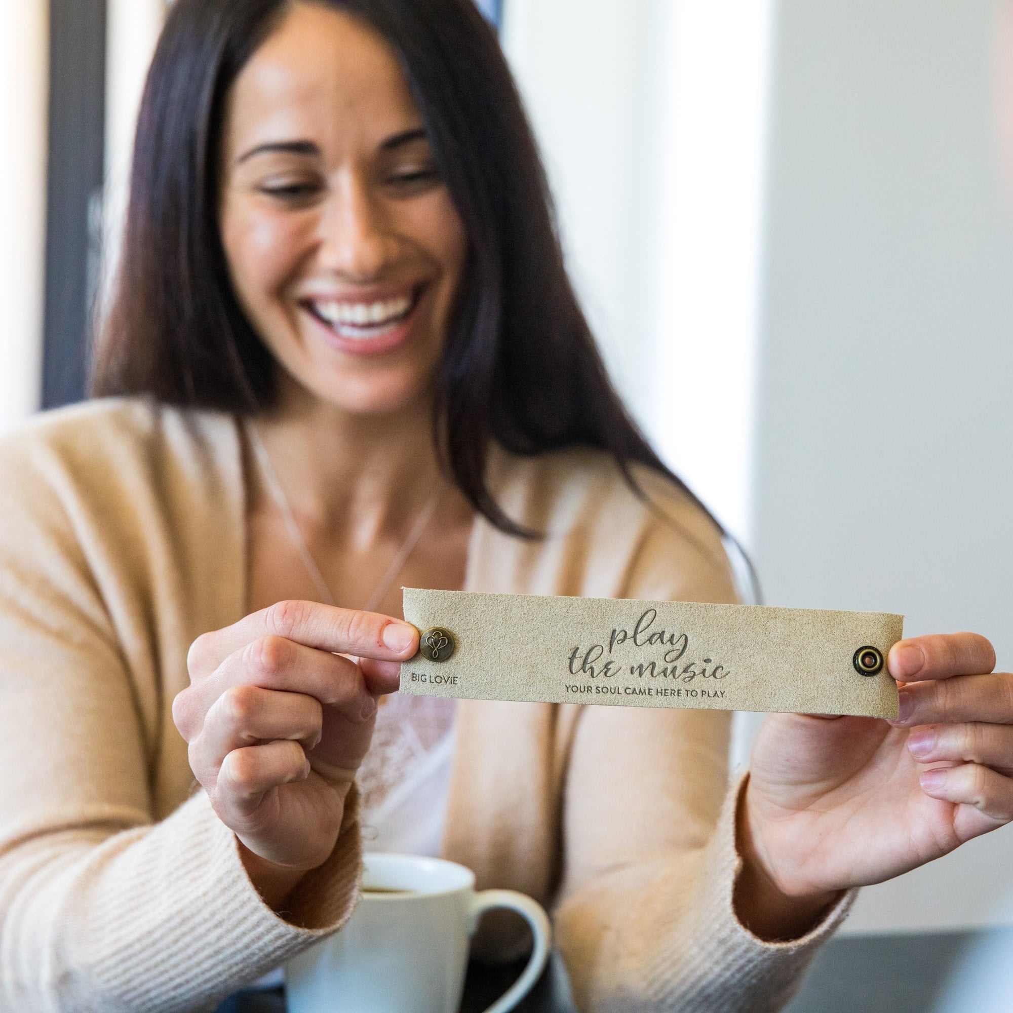 Woman smiling drinking coffee, holding up LoveSnap