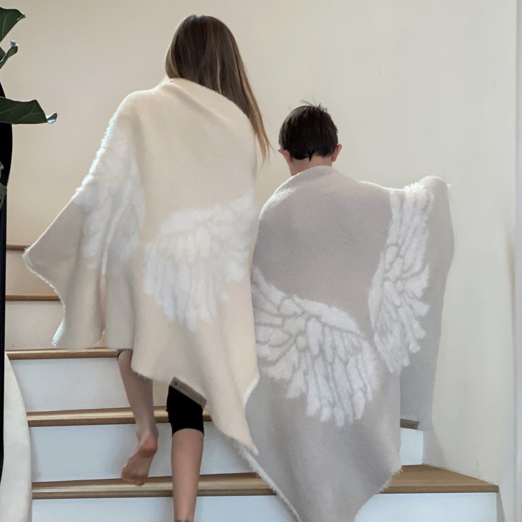 Two children wearing BIG LOViE Little Dream Collection Wings in Ivory and Silver waling up steps